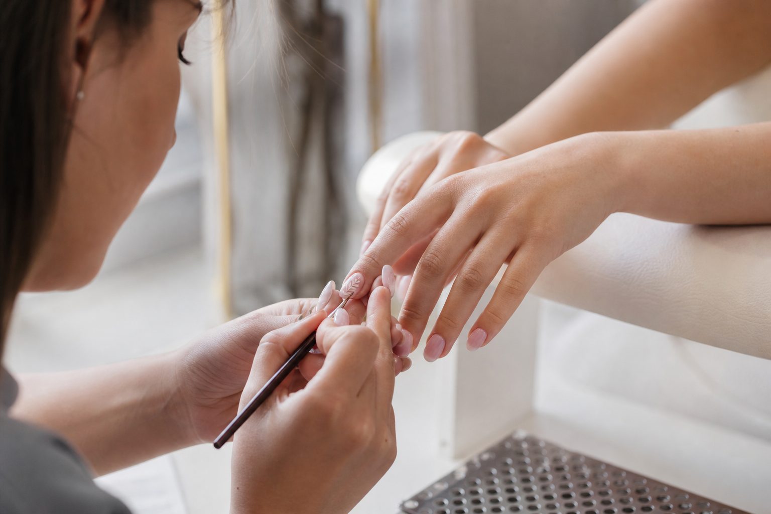 Riley hand-painting nail art on a client's set at Nova Nail Studio